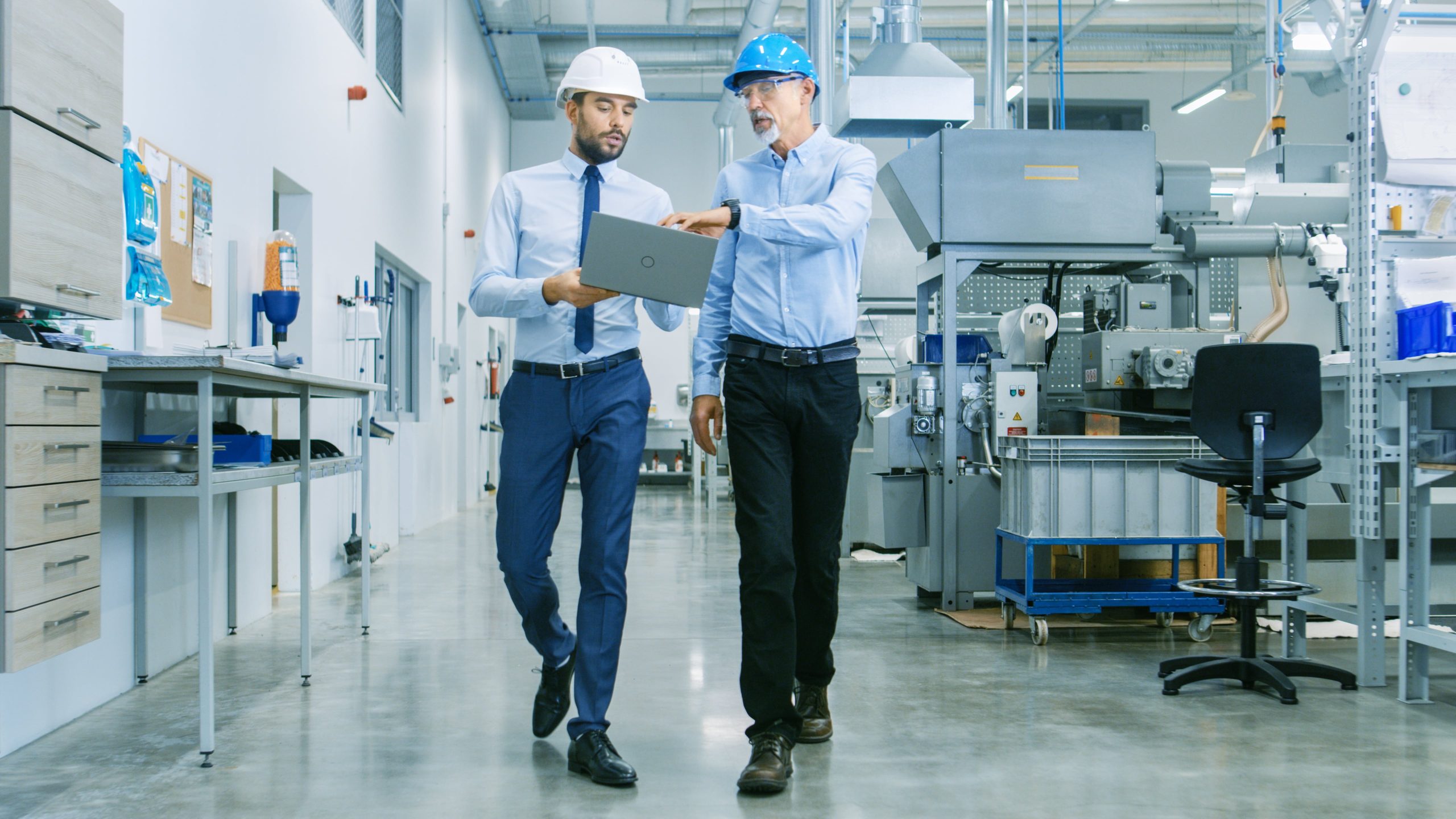two workers walking through a production plan looking at a production monitoring system dashboard